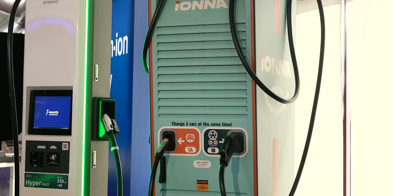 An IONNA Rechargery dispenser next to an Electrify America Hyper-FAST 350 kW unit, both labeled 'Charge 2 cars at the same time!'