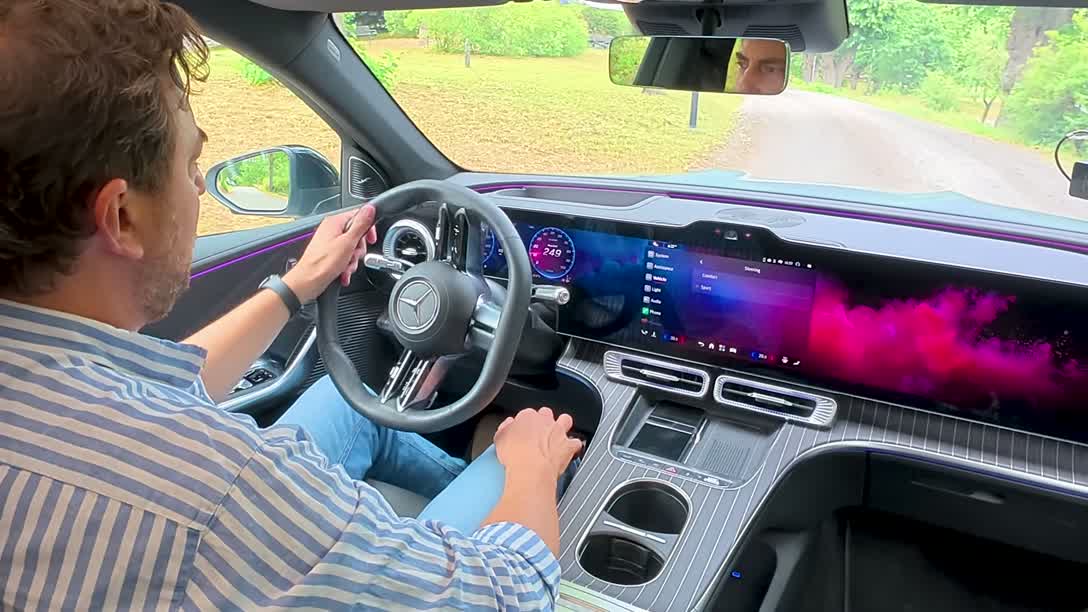 Over-the-shoulder view of the 39.1-inch MBUX Hyperscreen spanning the dashboard of the GLC 400, showing ambient purple lighting along the dash and Burmester speaker grille on top.